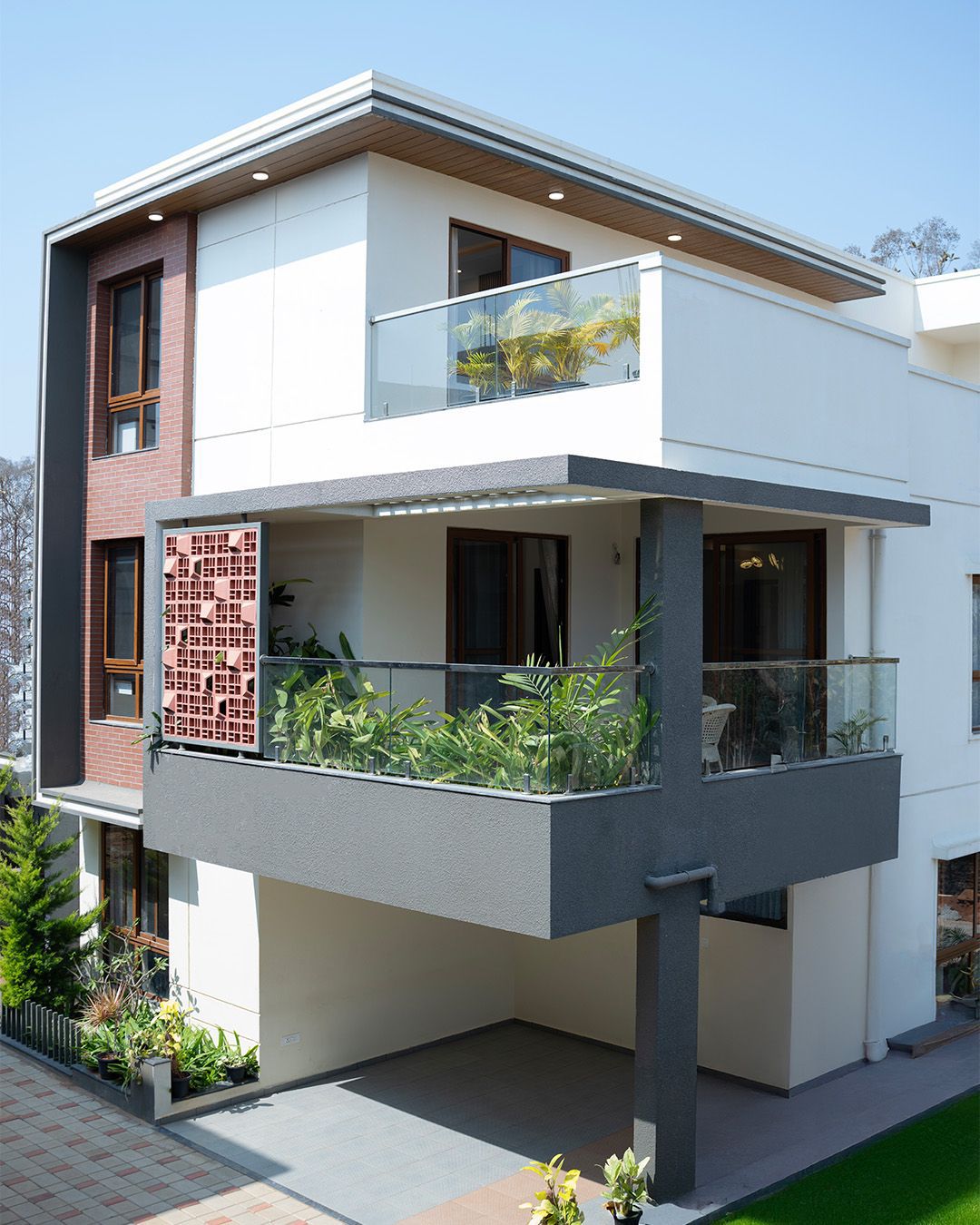 Spring Woods villa exterior with red clay jali facade and glass balcony